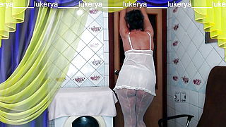 A hot housewife in the kitchen wears white transparent pantyhose without panties and a white peignoir in which her tummy